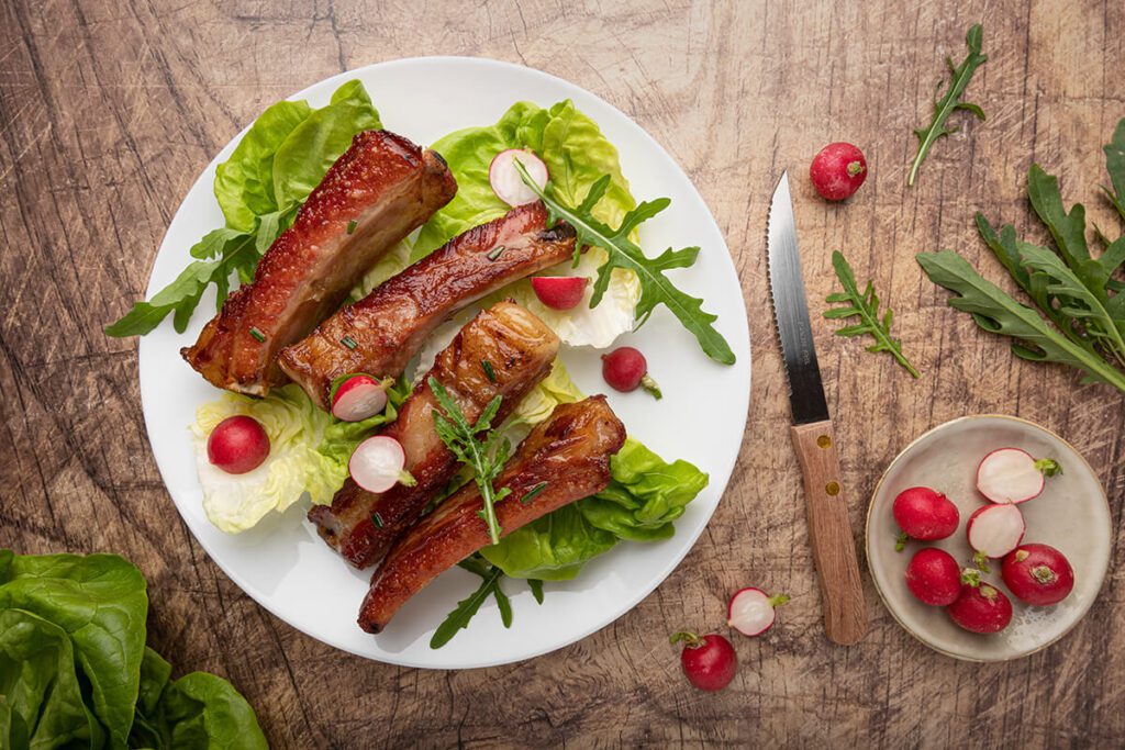 Piatto di costine alla griglia con insalata e pomodorini