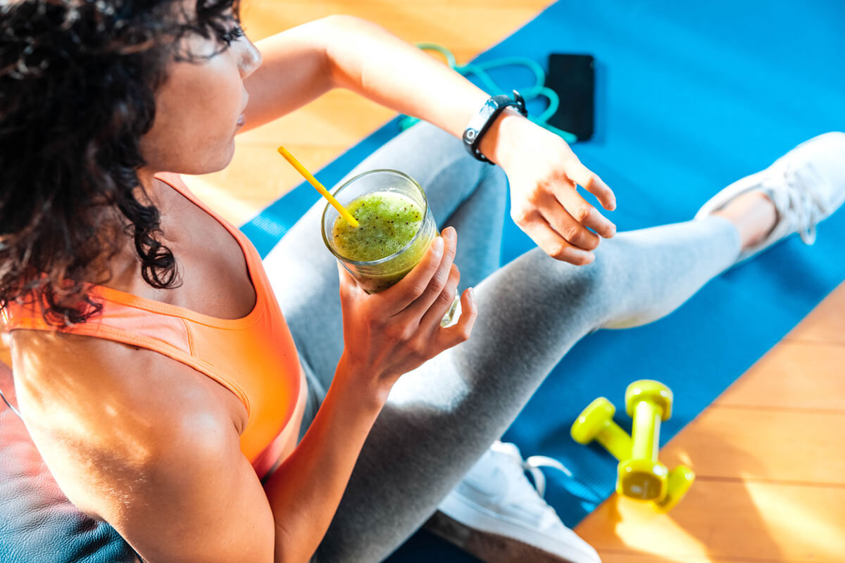 Ragazza sportiva fa una pausa con shake dall'allenamento